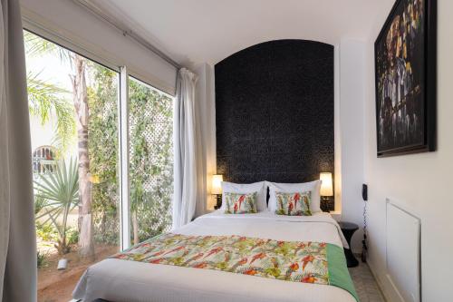 a bedroom with a large bed and a large window at Riad Zyo in Rabat