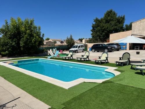 a swimming pool with chairs and a parking lot with cars at VILLA RURAL con amplia piscina in Campillo de Altobuey