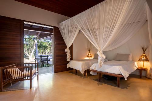 two beds in a bedroom with curtains over them at Guest House - Praia de Itapororoca in Trancoso