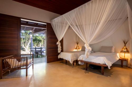 due letti in una camera da letto con tende sopra di Guest House - Praia de Itapororoca a Trancoso