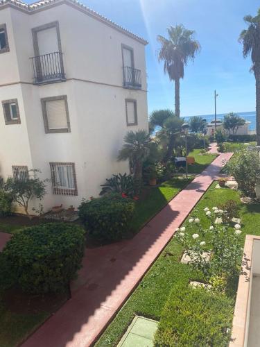a white house with palm trees and a sidewalk at Casa Pandora Apartamento Duplex Atico, primera línea de playa Torrox in Torrox Costa