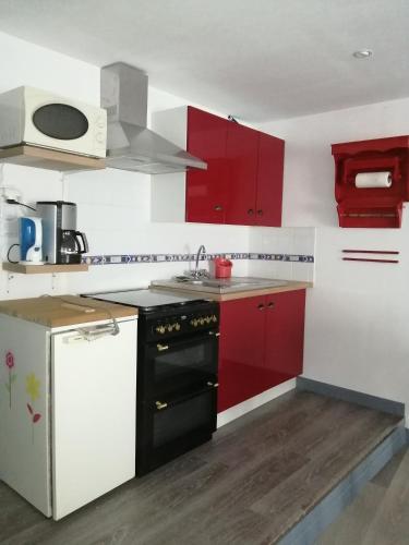 La cuisine est équipée de placards rouges et d'une cuisinière noire. dans l'établissement à 2 pas du centre ville, à Parthenay