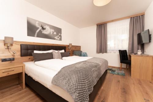 a bedroom with a bed and a desk and a television at Alpenchalet Oetztal in Oetz