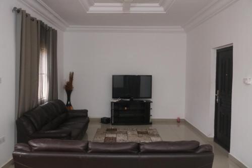 Una sala de estar con un sofá y un televisor de pantalla plana. en Koring Residence at Dalaba Estate, en Jarbang