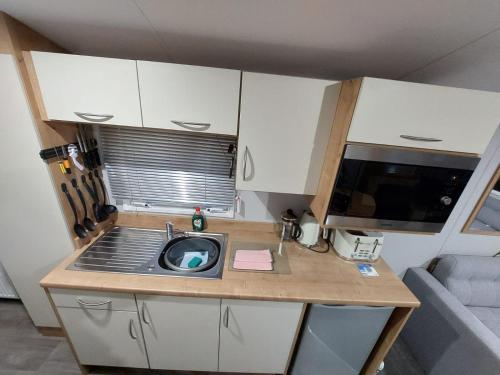 una pequeña cocina con fregadero y microondas en KEE Holiday Home Caravan en Great Yarmouth