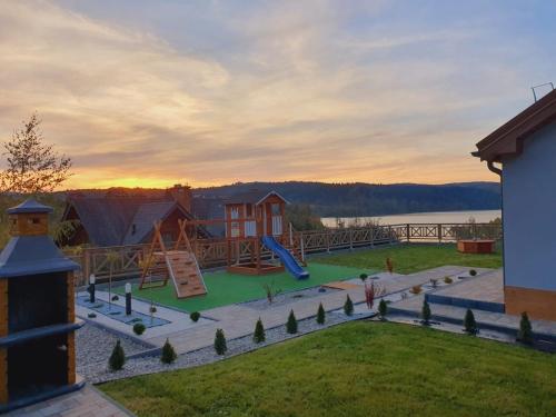 vistas a un parque infantil con una casa en Domki Na Wzgórzu Słońce JACUZZI SAUNA ROWERY, en Zawóz