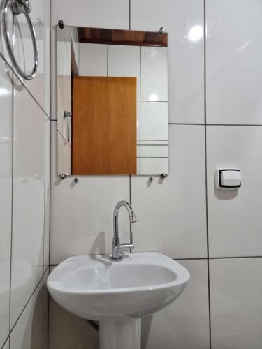 ein Badezimmer mit einem weißen Waschbecken und einem Spiegel in der Unterkunft Estalagem Do Luar in Monte Verde