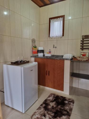 a kitchen with a white refrigerator and a counter at Estalagem Do Luar in Monte Verde