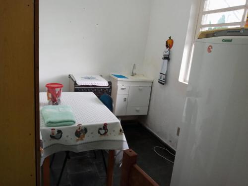a small white kitchen with a table and a window at Hostel Cantinho da Paz in Caxambu