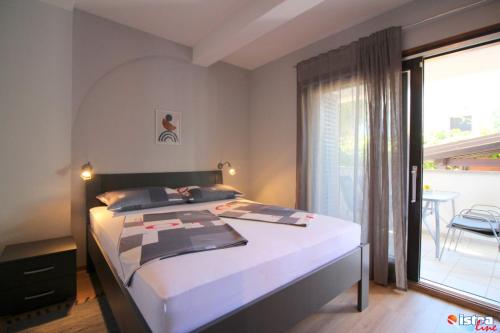 a bedroom with a bed and a large window at Dr. IGDA Apartments in Poreč