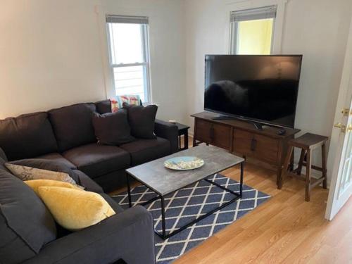 a living room with a couch and a flat screen tv at Cute yellow 2-BR bungalow w/free garage, free WiFi in Milwaukee