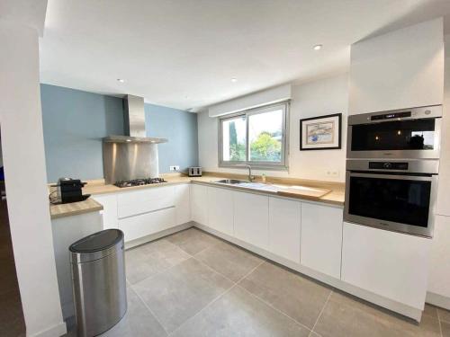 une grande cuisine avec des placards blancs et un évier dans l'établissement Charmante maison contemporaine – 300m des plages, à Larmor-Plage