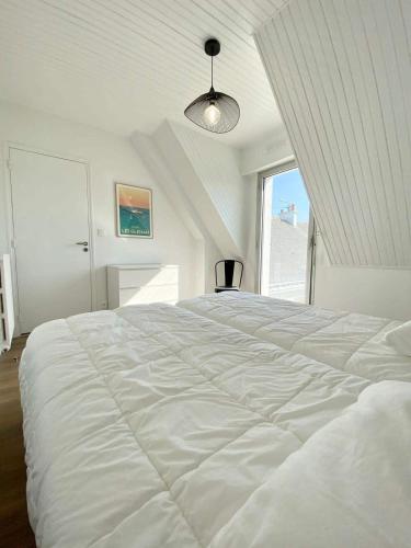 un grand lit blanc dans une chambre avec une fenêtre dans l'établissement Charmante maison contemporaine – 300m des plages, à Larmor-Plage