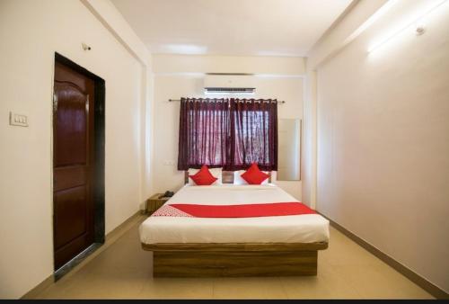 a bedroom with a bed with red pillows and a window at Primrose Guest House in Pune