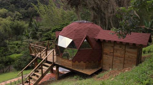 een klein huis met een rood dak op een heuvel bij FINCA CELESTIAL in Pacho