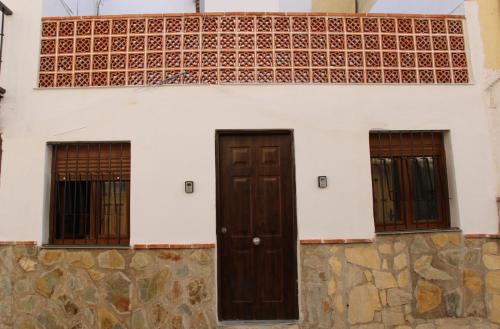 une maison avec deux portes et un mur en pierre dans l'établissement San Amador, à Martos