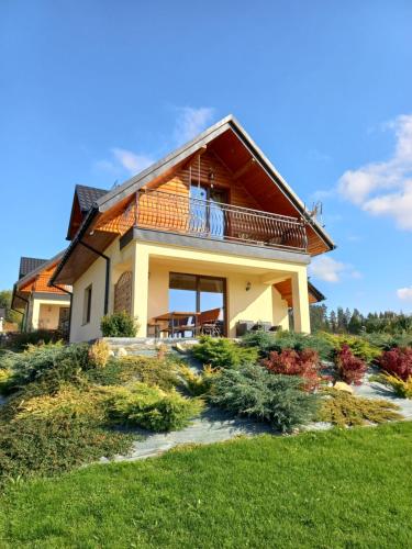 a house with a balcony on top of a yard at Domek na Hubce 1 in Maniowy