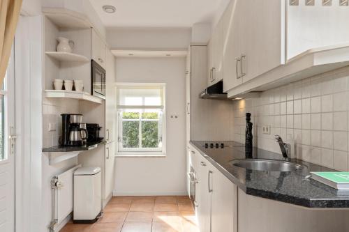 a white kitchen with a sink and a window at Vakantiehuis 6p Meddo in Winterswijk-Meddo
