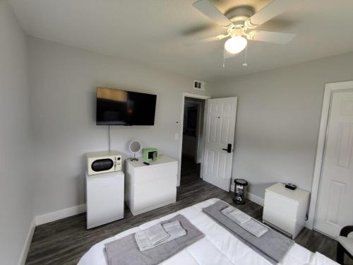 a white bedroom with a bed and a flat screen tv at Roosevelt Inn in Jacksonville
