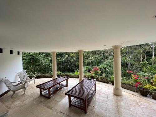 a porch with two benches and a chair and trees at Balian Bliss Retreat Bungalow & Villas in Balian
