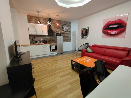 a living room with a red couch and a kitchen at Les Lofts De Provins: Apt 4 in Provins