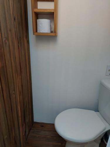 a bathroom with a white toilet and a wooden cabinet at Chalé Sunset Taipu de Fora in Marau