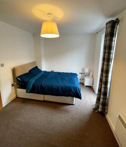 a bedroom with a blue bed and a window at Town centre flat in Darlington (free Parking) in Darlington