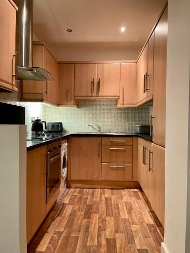 uma cozinha com armários de madeira e piso de madeira em Town centre flat in Darlington (free Parking) em Darlington