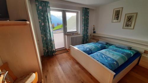 Bett in einem Zimmer mit Fenster in der Unterkunft Ferienwohnung Zwoelferblick in Bramberg am Wildkogel