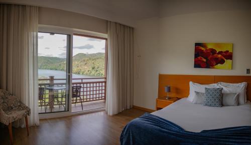 a bedroom with a bed and a balcony with a view at Hotel Rural Quinta da Conchada in Aguieira