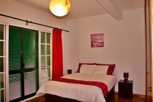 a bedroom with a bed and a window with green shutters at Ivone Madeira Guest House in Funchal