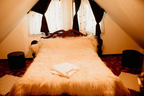 a bedroom with a large furry bed with two books at Casa Mario in Dragoslavele