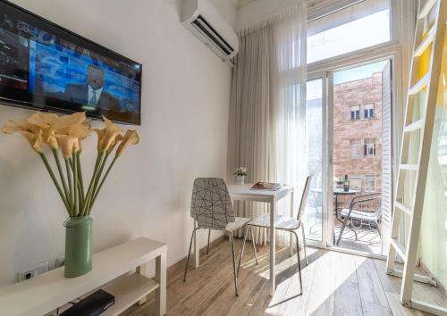 a living room with a table and a tv on the wall at Paamonim Studios in Jerusalem