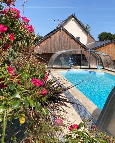 - une piscine à côté d'une maison ornée de fleurs roses dans l'établissement L'Escale Normande, à Saint-Jean-des-Champs