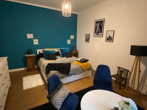 Schlafzimmer mit einem Bett mit blauen Wänden und blauen Stühlen in der Unterkunft Belle Chambre Privée - Sdb - cuisine partagée - Wifi - Jardin in Wissembourg