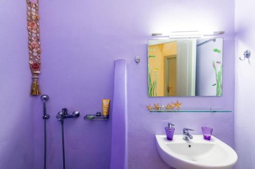 a purple bathroom with a sink and a mirror at Anastasia Home in Triandáros