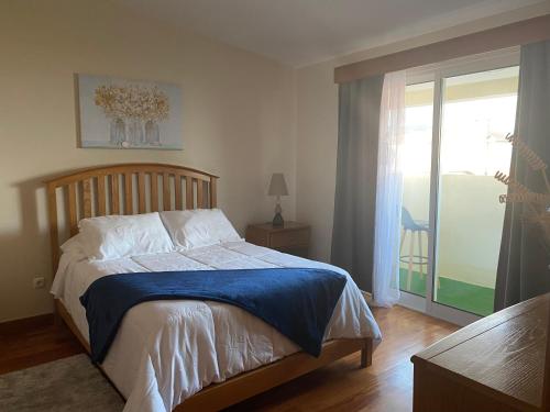 a bedroom with a bed and a sliding glass door at Mountain and Ocean View in Água de Alto