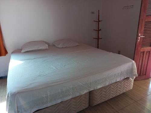 a bed with white sheets and pillows in a room at Paracuru HolaOnda WaveHostel in Paracuru