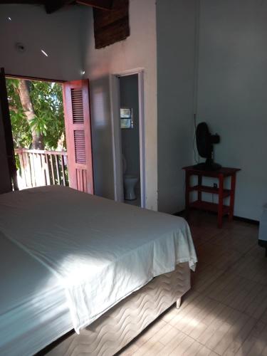 a bedroom with a white bed and a balcony at Paracuru HolaOnda WaveHostel in Paracuru