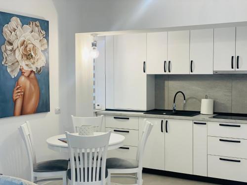 uma cozinha com armários brancos e uma mesa e cadeiras em Luxury Prince em Câmpulung Moldovenesc