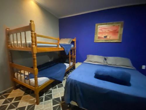 a bedroom with two bunk beds and a blue wall at Casa Luke Paraty - Praia e cachoeira in Paraty