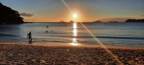 Un uomo in piedi sulla spiaggia a guardare il tramonto di Casa de Praia com piscina a Boicucanga