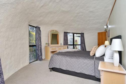 1 dormitorio con 1 cama, escritorio y ventanas en Koepel House - Christchurch Holiday Homes, en Christchurch