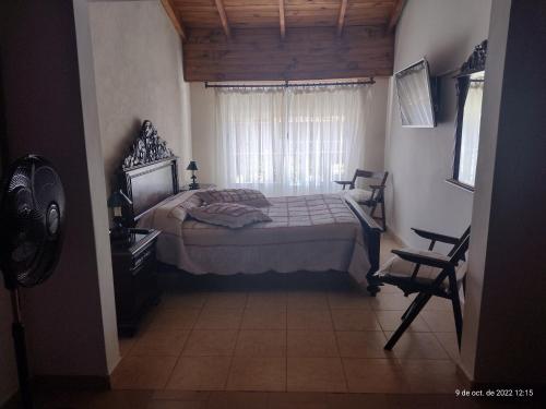 1 dormitorio con cama, ventana y silla en Mi casita en Tandil