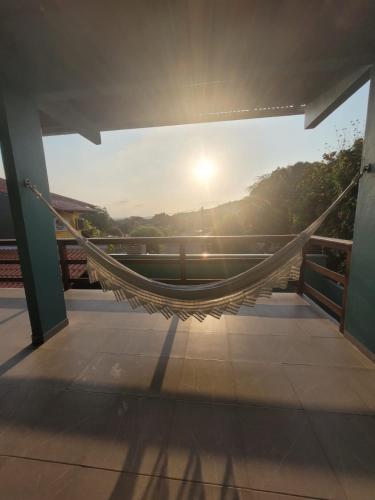 a hammock on a balcony with the sun in the background at Pousada Tauari in Alter do Chao