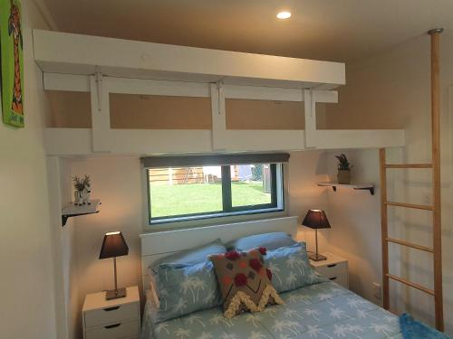 1 dormitorio con litera y ventana en Red Beach Garden Cottage, en Red Beach