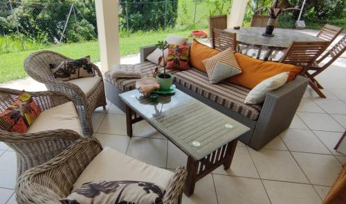 um pátio com cadeiras de vime, um sofá e uma mesa em Chambre privée près des plus belles plages du Nord em La Trinité