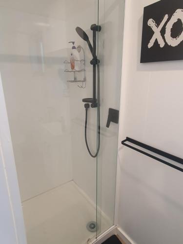 a shower in a bathroom with a glass door at Red Beach Garden Cottage in Red Beach