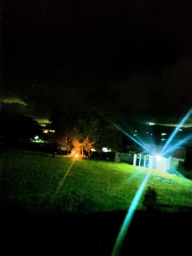 a field at night with lights on a house at Camping Las Acacias in Guatavita