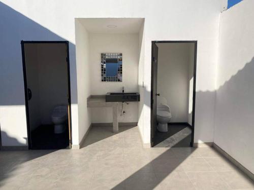 La salle de bains est pourvue de 2 toilettes, d'un lavabo et d'un miroir. dans l'établissement Hermoso apartamento con alberca, 